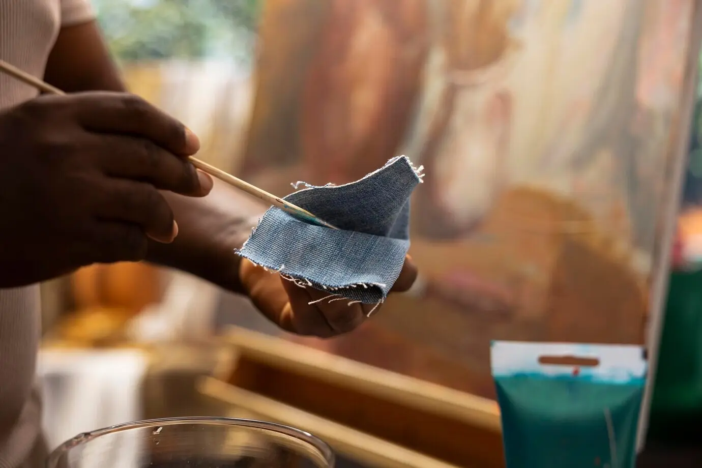 Erfahrener Maler wischt den Pinsel an Denimstoff ab, um die Farben zu reinigen.