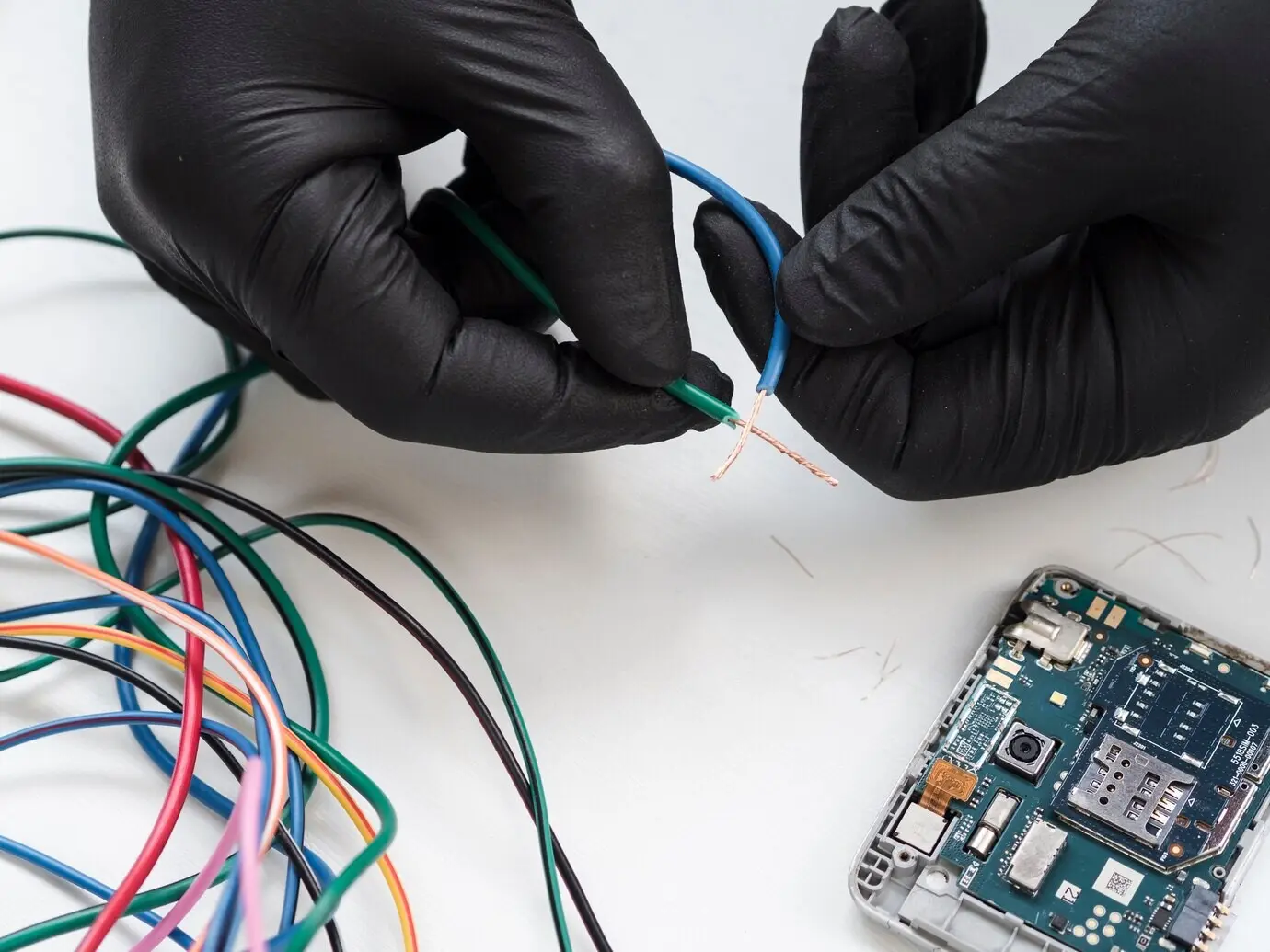 Hände mit schwarzen Handschuhen halten Draht.