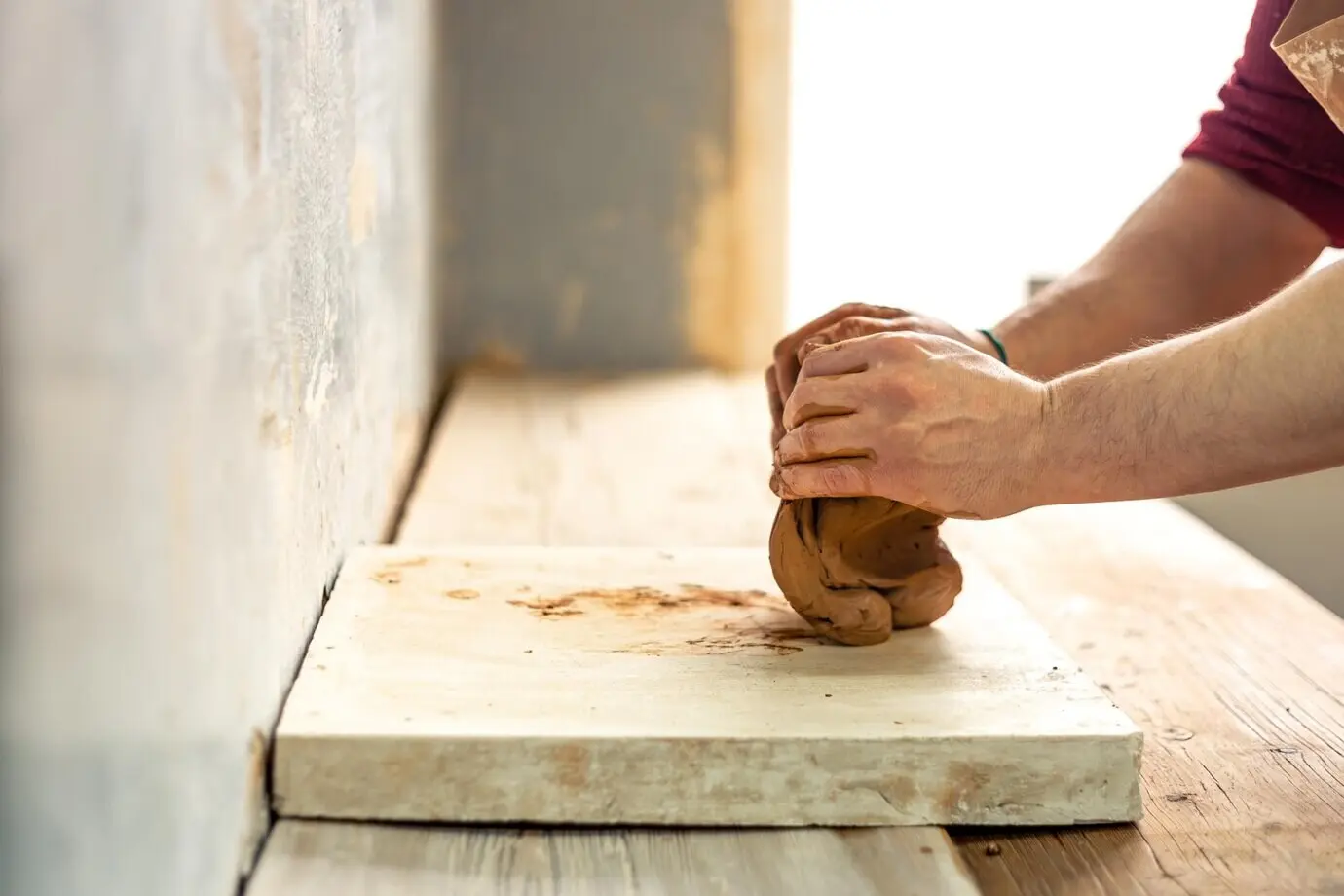 Keramiker/Töpfer bei der Arbeit, modelliert aus Ton, bereitet sich auf das Töpfern vor, Ton in den Händen.